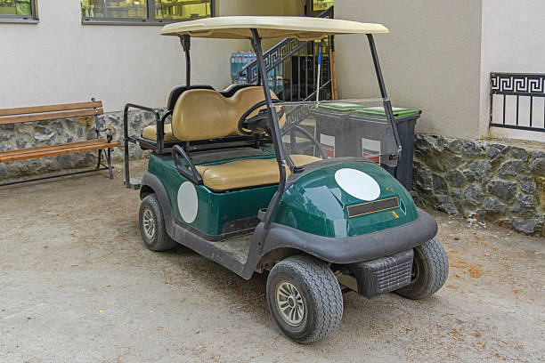 Senior man on golf course driving golf cart at sunrise