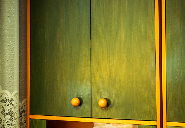 Vintage green wooden cabinet doors featuring round yellow knobs and yellow trim, reflecting a retro style and offering a nostalgic look into interior design