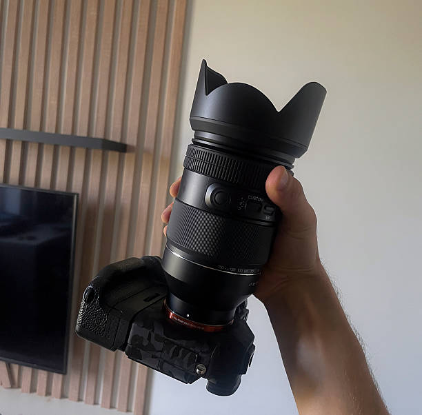 istock Person holds a professional camera with a large lens in a clean, simple interior space 2252782436
