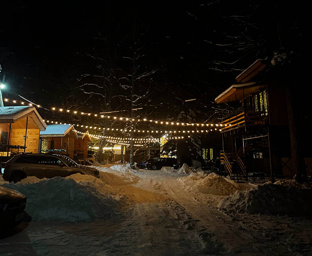 istock Snow covers the ground while warm lights illuminate a pathway between cabins at night 2252782482