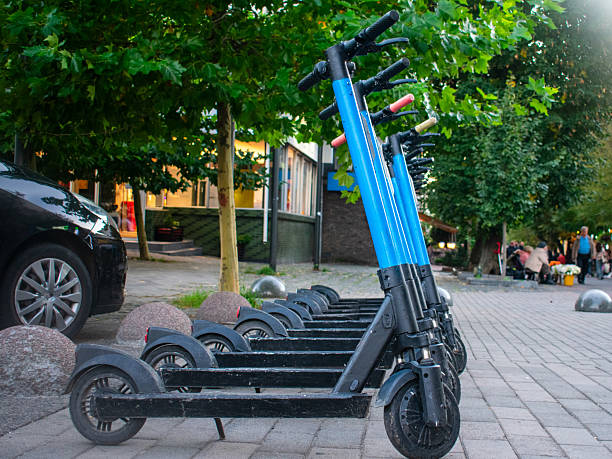 istock Several electric scooters lined up for use next to a busy street and trees 2252782599