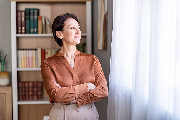 istock Mature woman looking out window thinking about future 2252783012