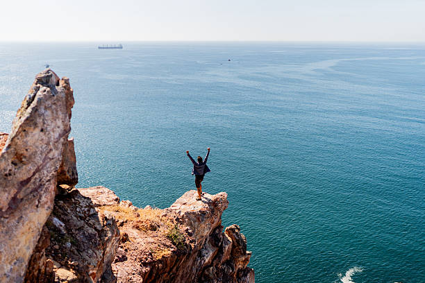 Mid adult climber man celebrating on mountain peak