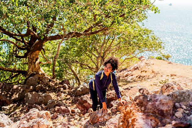 Two young women hiking and climbing at large boulders at Anja Community Reserve, one women is looking at camera, Madagascar