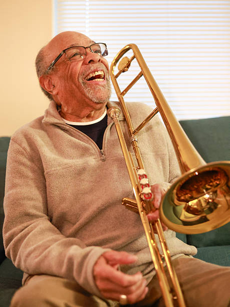 Over shoulder shot of young African American man playing trombone on stage with his jazz music band