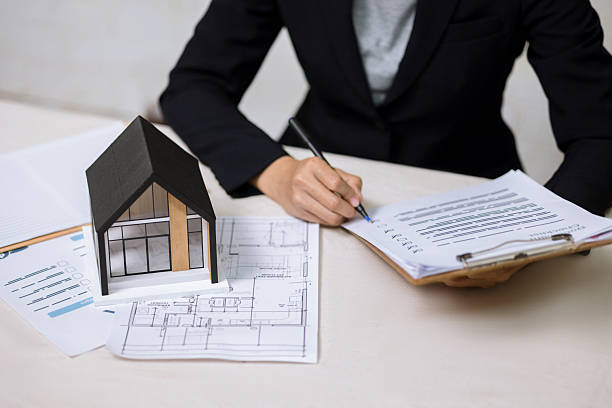 istock Real estate agent writing on document checklist with house model and blueprints. 2252786324