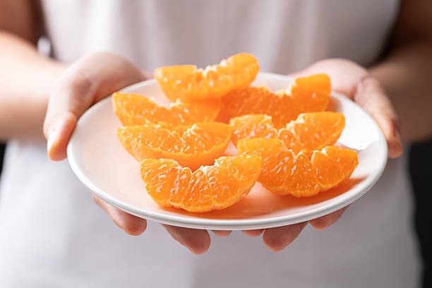 istock Sliced Mandarin orange fruit on plate holding by hand 2252793130