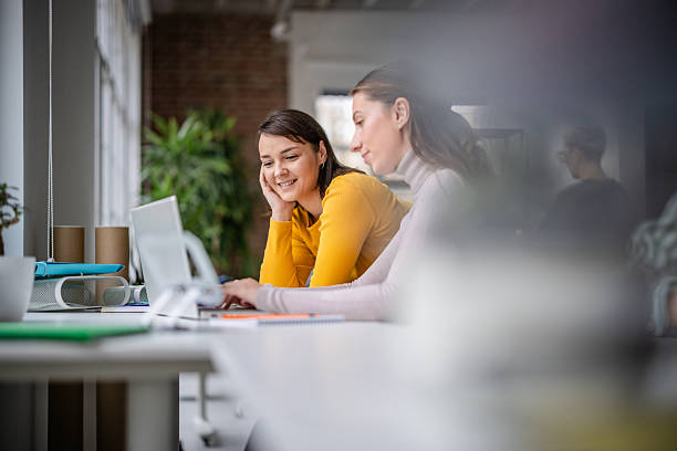 istock Engaged adults working together in a modern office setting to complete tasks and discuss ideas with technology 2252797358