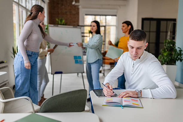 istock Professionals engage in teamwork and discussion while one colleague writes notes in modern office setting during work hours 2252800120