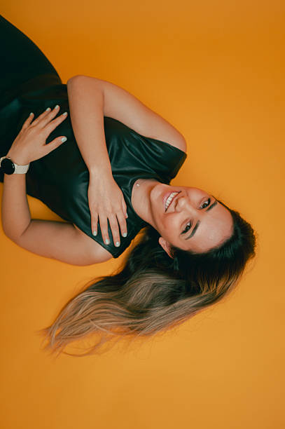 Calm young woman in summer yellow dress isolated over beige background, copy space for text, Tired female suffering from backache or back pain, massaging lower back by herself. Side view
