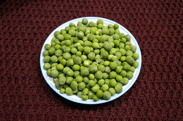 Top view of white bowl full of frozen peas