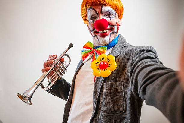 Clown smiling at camera holding trumpet and wearing colorful costume