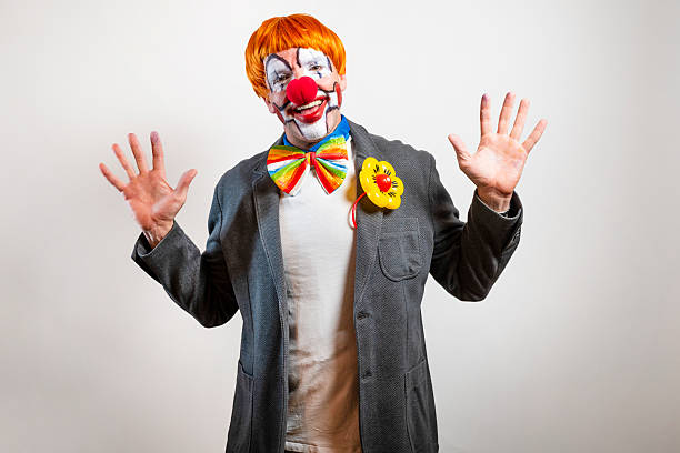 Man made up as clown with black bowler hat and colorful scarf during the Rosenmontag carnival parade in Cologne