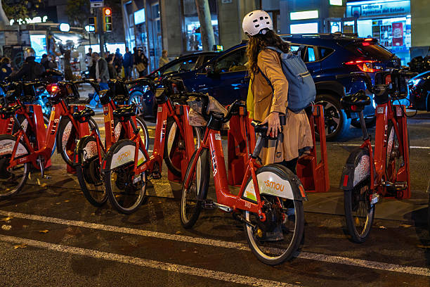 Barcelona, Spain-November 17, 2025. A user unlocking a red electric bicycle from the docking station of the public sharing system Smou or Bicing on a street in Barcelona, Spain.