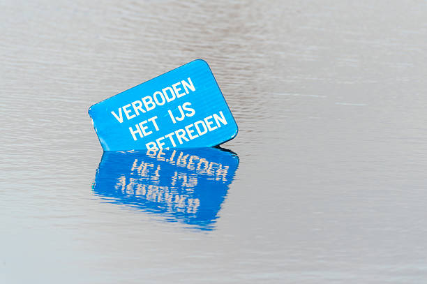 Ghent, Belgium - February 20, 2012. Partically submerged sign stating: Forbidden to walk on ice.