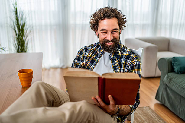 istock Happy man relaxing at home, reading a book 2252818036