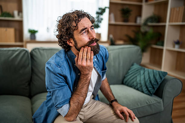 istock Man experiencing toothache pain at home on couch 2252818232