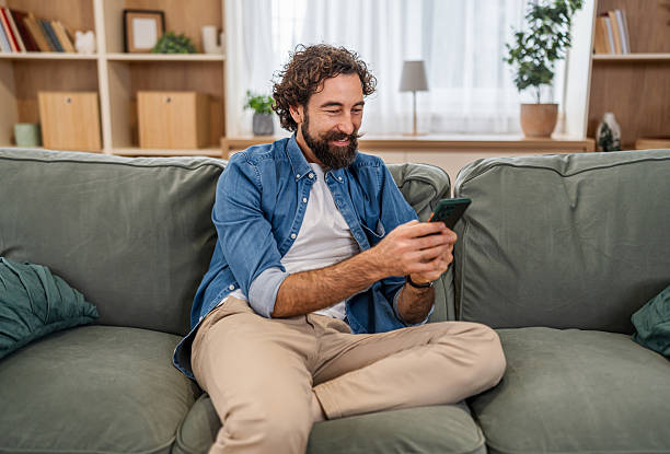 istock Man relaxing on couch checking phone at home 2252818329