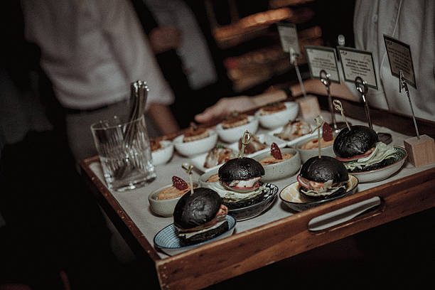 Mini black burgers being served to honored guests at a celebration.