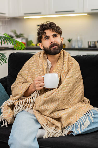 istock Indian man wrapped in blanket holding hot tea cup slowly drinking relaxing after hard work smiling 2252820730