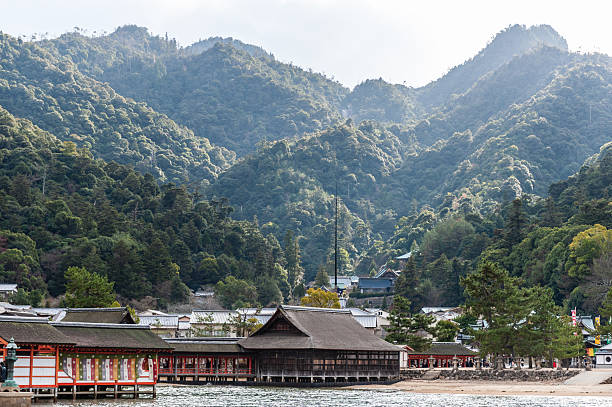 Hatsukaichi, Japan - December 31, 2019. Outdoor scene showing the beautiful mountain scenery of Miyajima island, with the Itsukushima Jinia Shrine in the foreground.