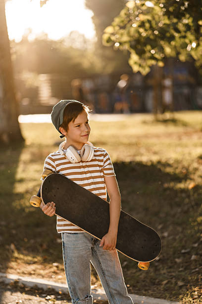 istock Young boy holding skateboard at sunset in park. 2252822465