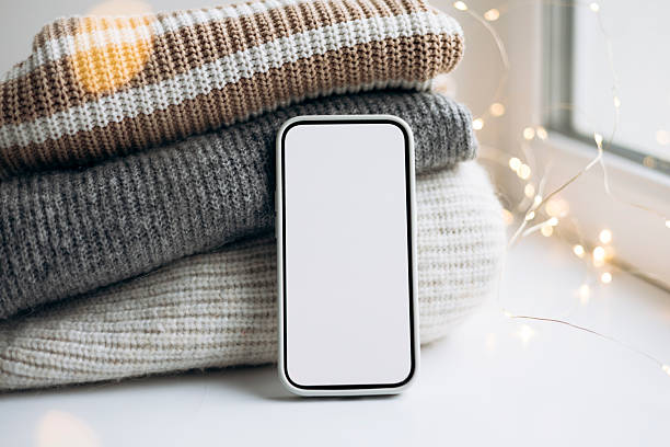 istock Smartphone mockup on cozy sweaters with festive bokeh lights. 2252823172