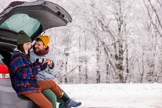 istock Couple using smart phone and drinking tea while taking winter vacation road trip break 2252823871
