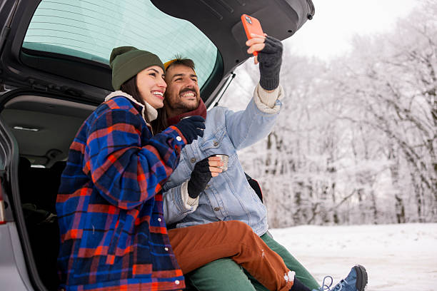 istock Couple using smart phone and drinking tea while taking winter vacation road trip break 2252823934