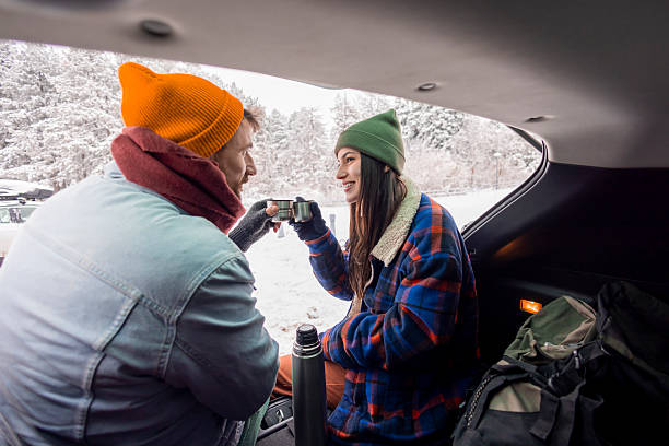 istock Couple taking a break while going for weekend vacation road trip, drinking hot tea in a car trunk 2252824296