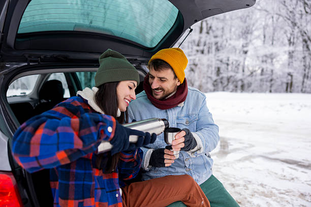 istock Couple taking a break while going for weekend vacation road trip, drinking hot tea in a car trunk 2252824368