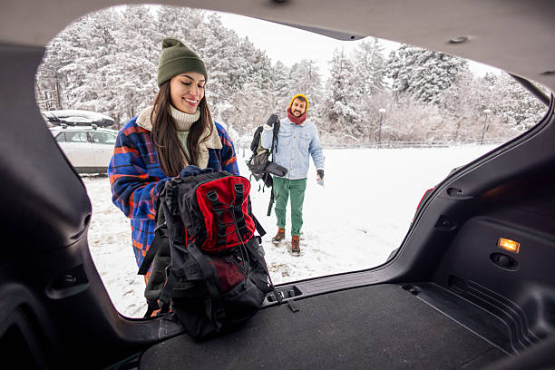 Young happy family taking out suitcases from a car trunk on a snowy day