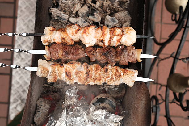 Chicken and meat shish kebab being cooked over coal fire on mangal, delicious food on grill, close up