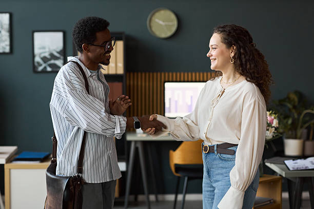istock Young Caucasian Woman Shaking Hands with Young Black Man in Office Setting 2252826977
