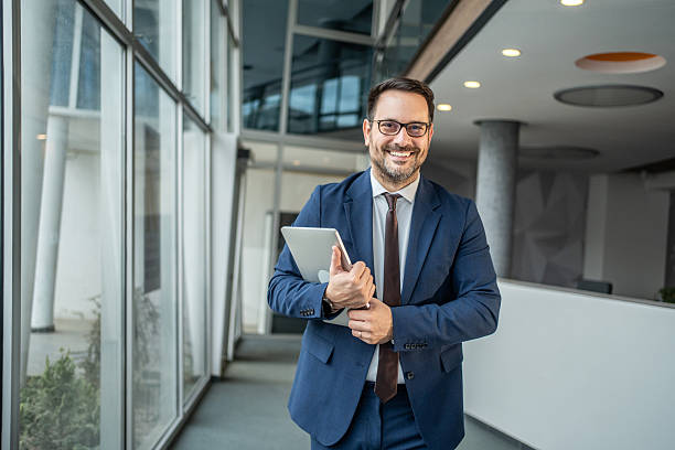 istock Professional businessman smiling holding tablet in modern office 2252831797