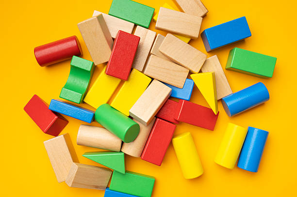 istock Wooden children's multi-colored bright construction set blocks of different shapes on yellow background. Montessori style cubes game for toddlers flat lay top view. Concept of learning and education 2252831817