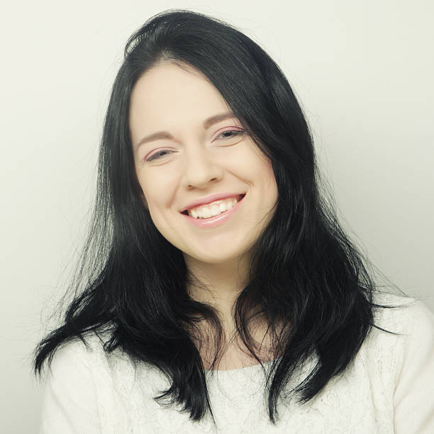 Half face of mature woman smiling at camera, man standing behind