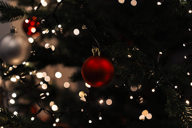 istock Red and silver ornaments are placed on a Christmas tree. Bright white lights are glowing among the branches. This scene is set in a warm indoor space during the holiday season 2252838103