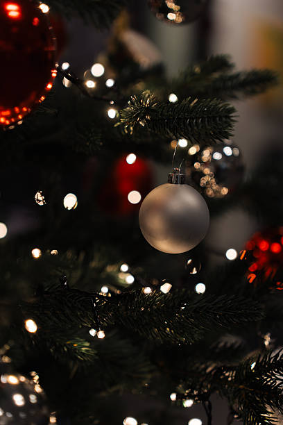 istock A Christmas tree stands adorned with shiny ornaments in red and silver. Strings of bright lights add a warm glow to the scene during the holiday season 2252838137