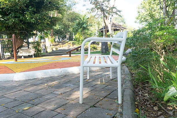 A white metal bench is prepared and served in public park.