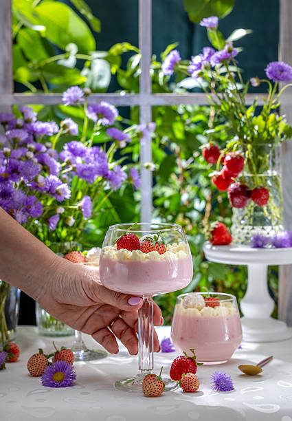 Hand holding strawberry mousse dessert with whipped cream