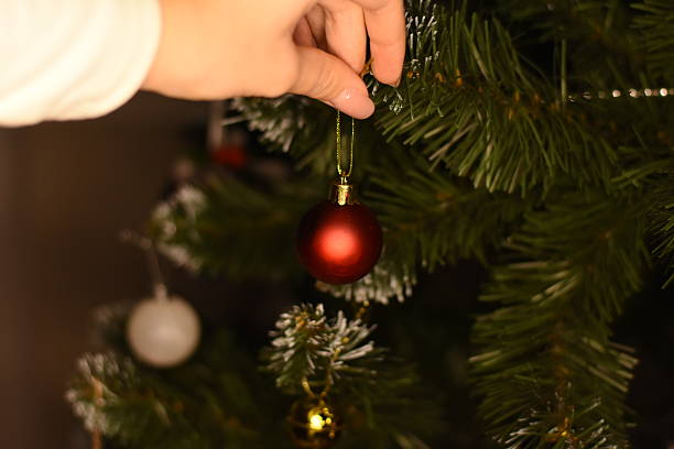 istock Hand hanging red Christmas ornament on tree 2252841962