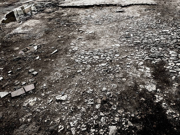 Devastation. Grunge background of broken asphalt. A crumbling old road with defects in black and white.