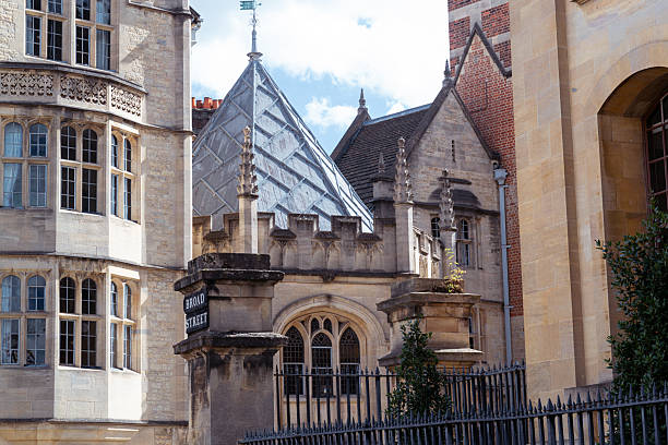 People stand next to the Meadow Building at Christ Church College in Oxford, England, UK on a cloudy day.
