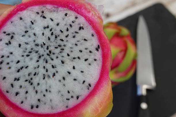 istock Dragon fruit half showing seeds with knife 2252860508