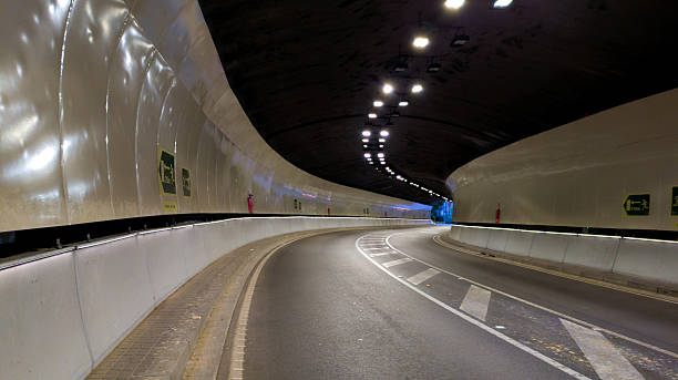 istock Empty underground road tunnel with a curving asphalt highway leading to a light at the end of the passage 2252862080