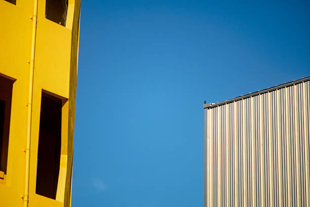 A vibrant architecture photo featuring a yellow building facade contrasting against a blue sky, highlighting modern design, geometric shapes, and urban character.