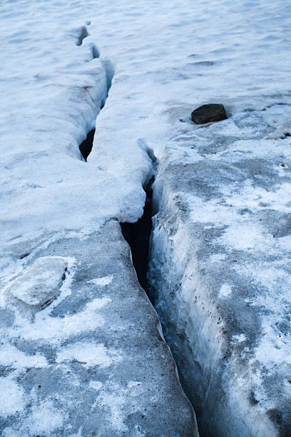 Close-up of a deep glacier crevasse cutting through melting ice and snow. Natural pattern formed by climate processes, symbolizing danger, instability, global warming, environmental change and extreme alpine conditions