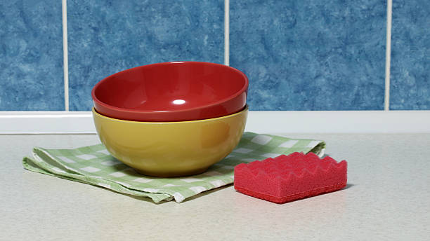 Stacking red and yellow ceramic bowls on checkered napkin with red sponge
