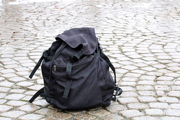 istock Black abandoned backpack resting on cobblestone street 2252866326